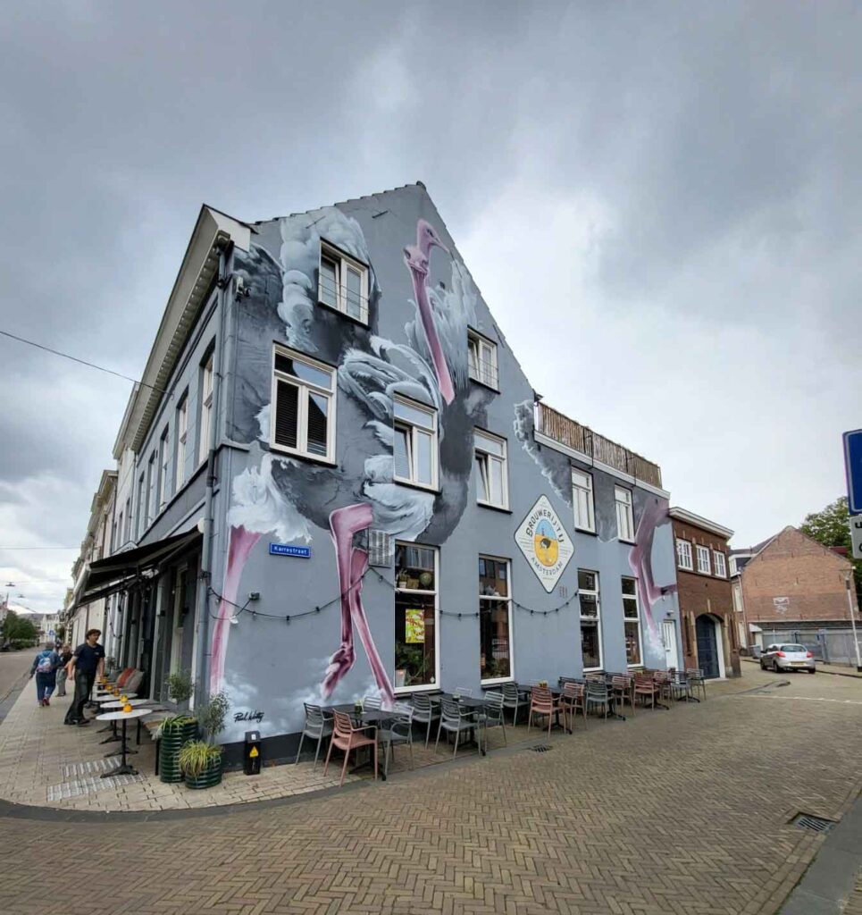 Tilburg: Wo Industriekultur auf Design und neue Ideen trifft 22 Großes Wandbild mit stilisierten Tiermotiven auf einer grauen Hausfassade in Tilburg.