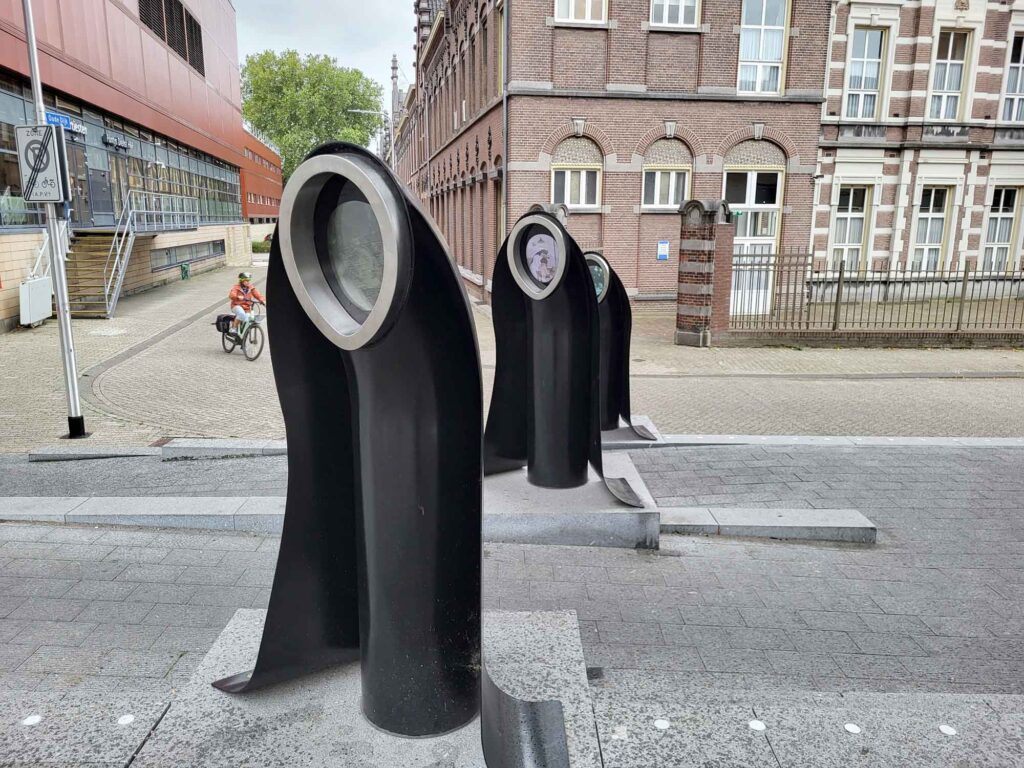 Tilburg: Wo Industriekultur auf Design und neue Ideen trifft 28 Drei schwarze Figuren des Kunstwerks „Zusters in Staal“ am Stadsforum in Tilburg mit integrierten Bildschirmen.