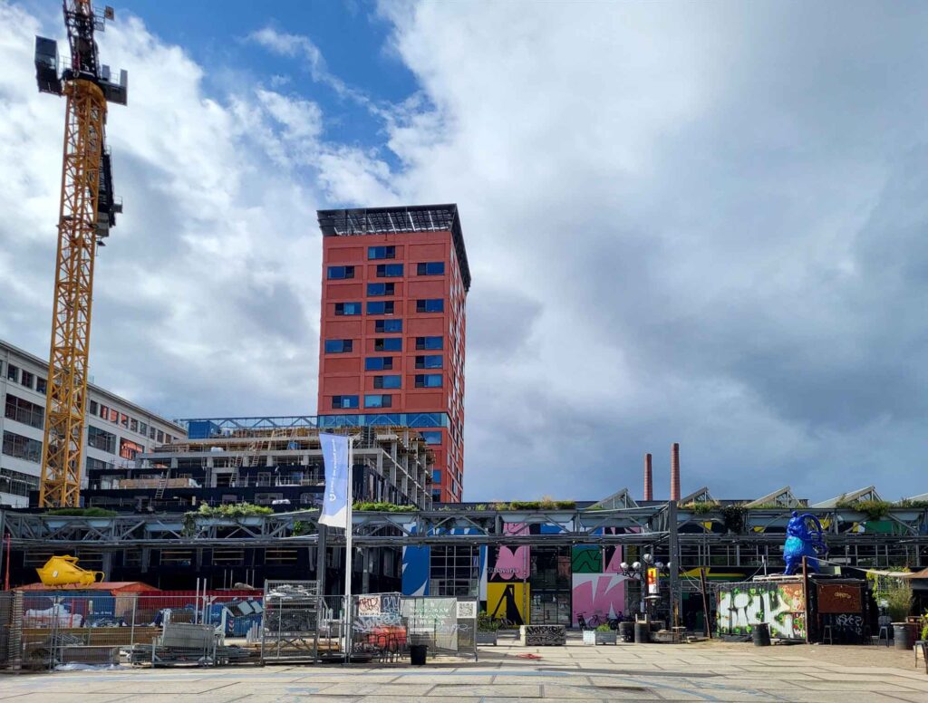 Eindhoven: Vom Philips-Erbe zur Zukunftsstadt 15 Baustelle auf Strijp-S mit Haasje-Over-Turm, Leidingstraat und Industriegebäuden unter wolkigem Himmel.