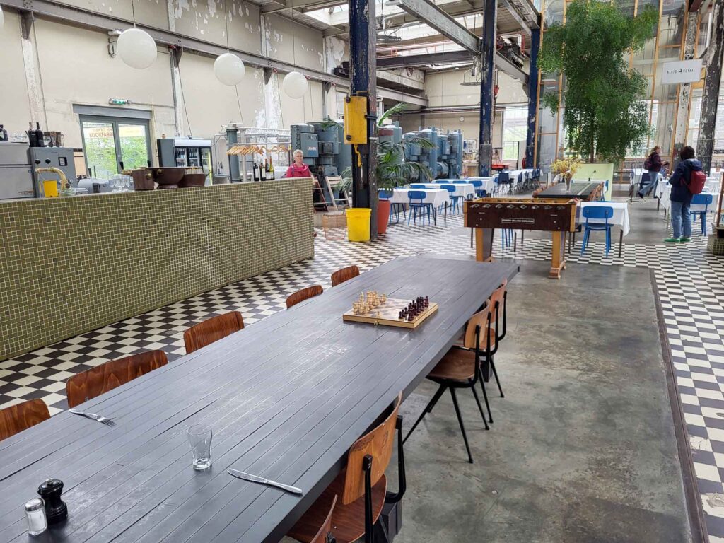 Eindhoven: Vom Philips-Erbe zur Zukunftsstadt 9 Gastraum von Radio Royaal in einer Industriehalle mit historischen Maschinen, langen Tischen und Schachbrettboden.