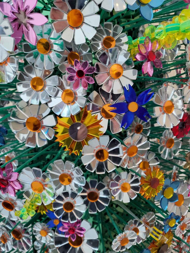 Eindhoven: Vom Philips-Erbe zur Zukunftsstadt 24 Nahaufnahme einer farbenfrohen Installation aus spiegelnden Blumen, grünen Stielen und kleinen Insektenmotiven.