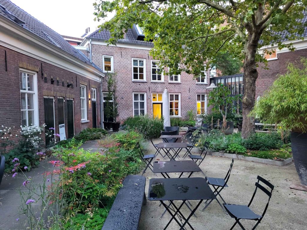 Eindhoven: Vom Philips-Erbe zur Zukunftsstadt 21 Begrünter Innenhof der Kazerne in Eindhoven mit Tischen, Stühlen und historischen Backsteingebäuden.