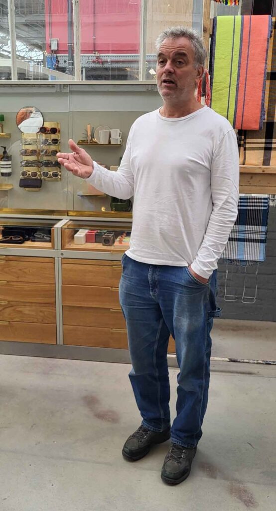 Eindhoven: Vom Philips-Erbe zur Zukunftsstadt 34 Piet Hein bei einer Führung in einem Designshowroom mit Schauvitrinen und farbigen Textilien.