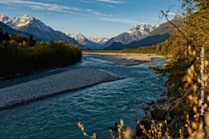 Wildfluss Lech mit breitem Kiesbett, bewaldeten Ufern und Bergen im Tiroler Lechtal