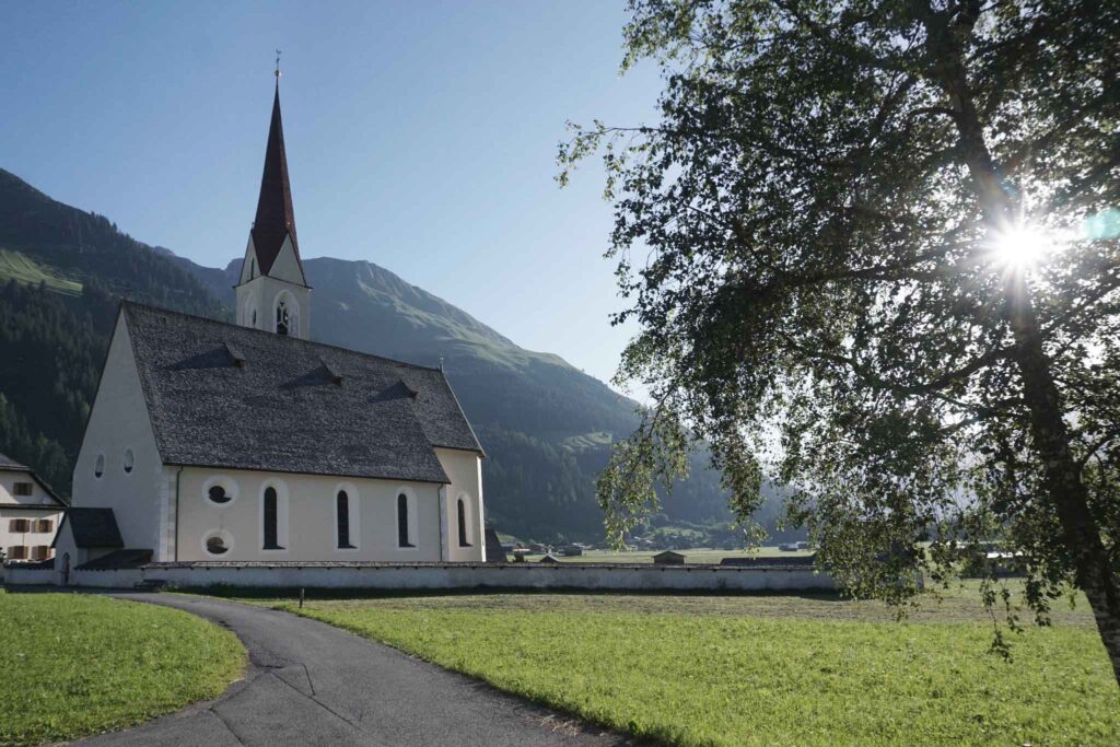Auf den Spuren des Malers Max Kuhn: Das Lechtal rund 160 Jahre später 18 Pfarrkirche St. Nikolaus in Elbigenalp mit Berghängen im Hintergrund