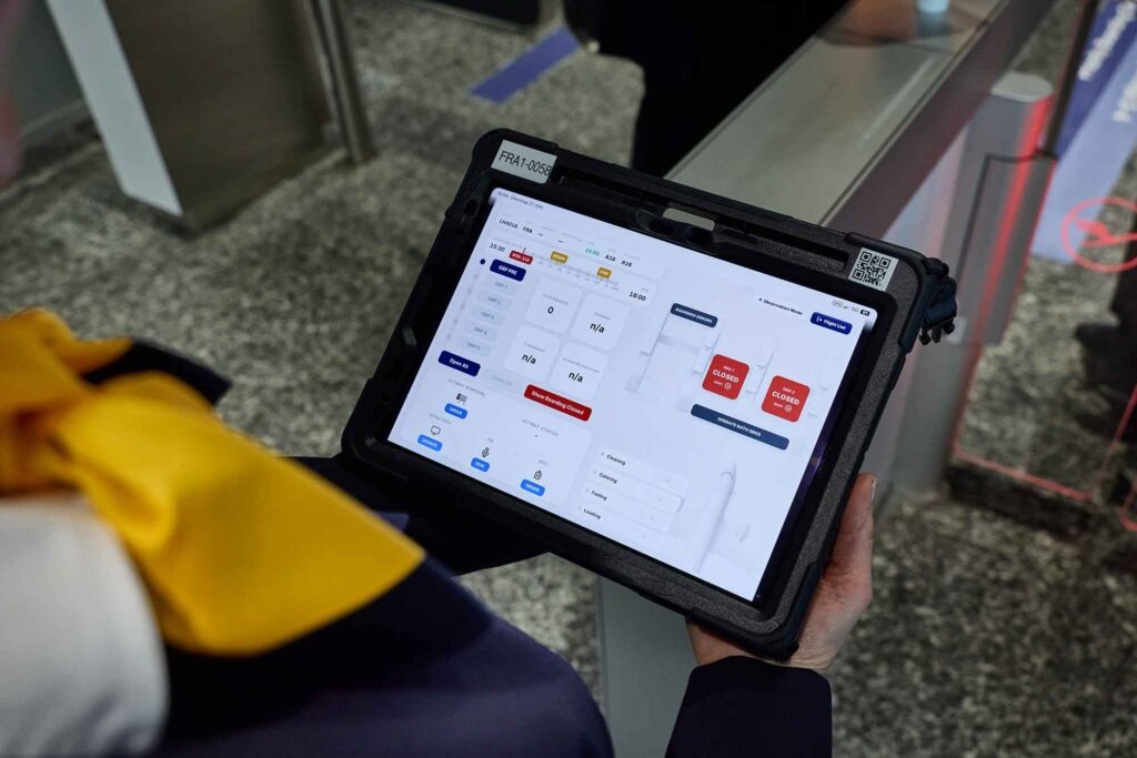 Gate of the Future: Lufthansa und Fraport testen das Boarding der Zukunft 4 Lufthansa-Mitarbeiterin von hinten mit einem Tablet, das die digitale Boarding-Steuerung am Gate A16 des Frankfurter Flughafens zeigt.